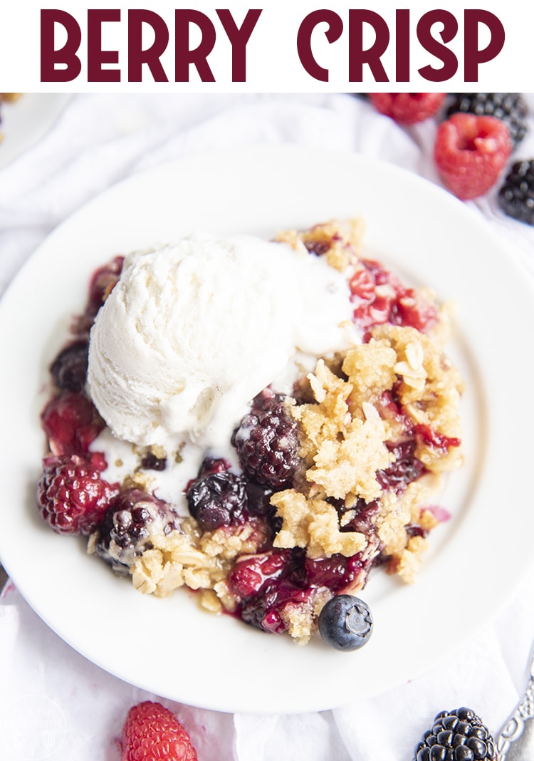 A plate of berries with a streusel topping and vanilla ice cream. 