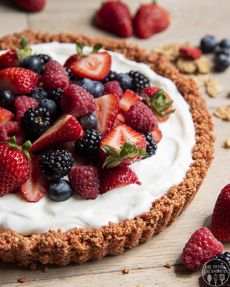 A close up of a breakfast tart topped with yogurt and fresh berries.
