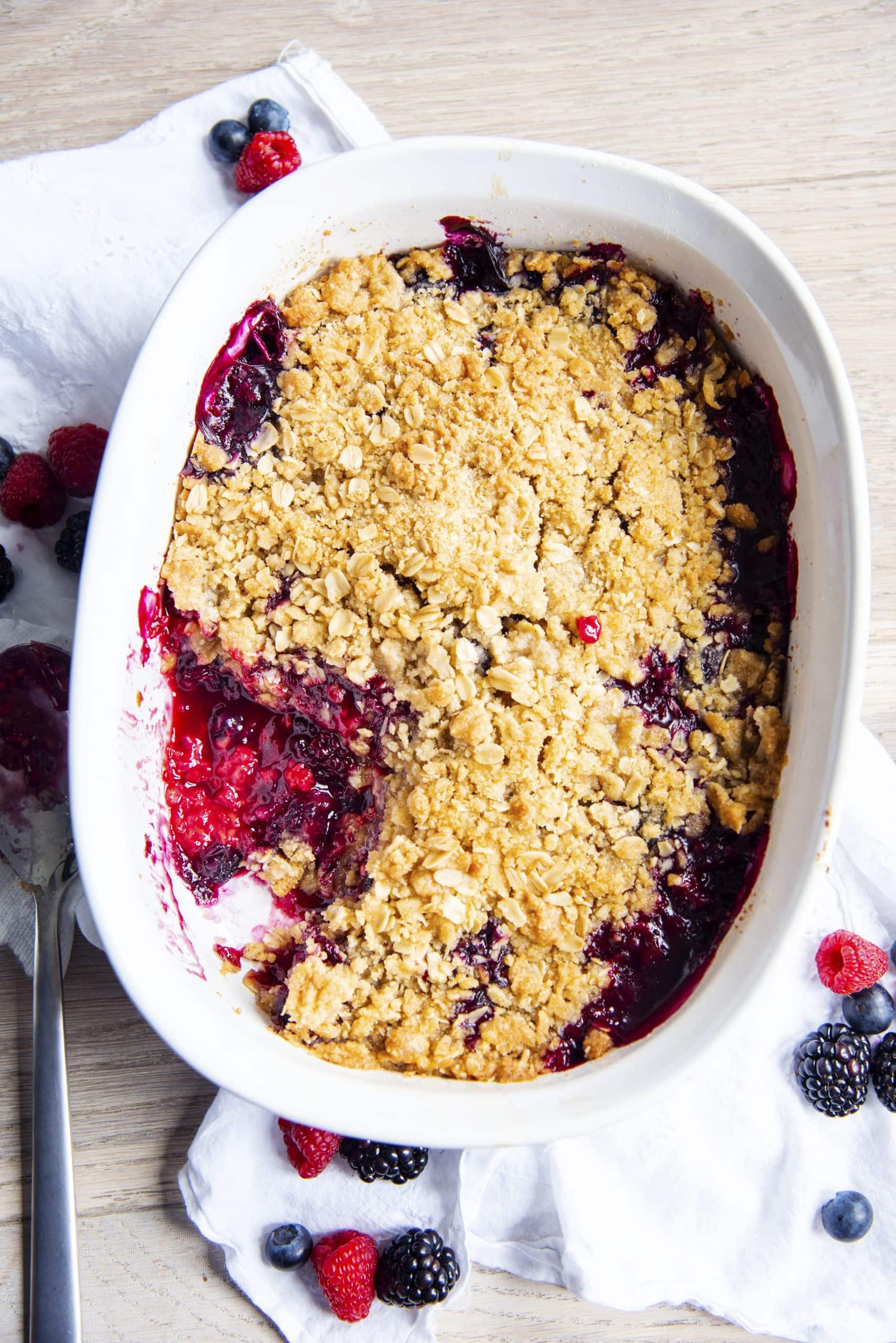 A white baking pan with berry crumble in it.