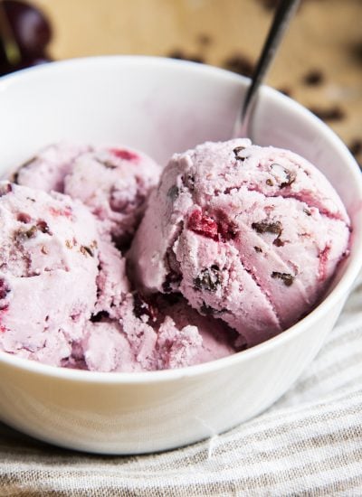 A bowl of scoops of cherry ice cream with chocolate chips in it.