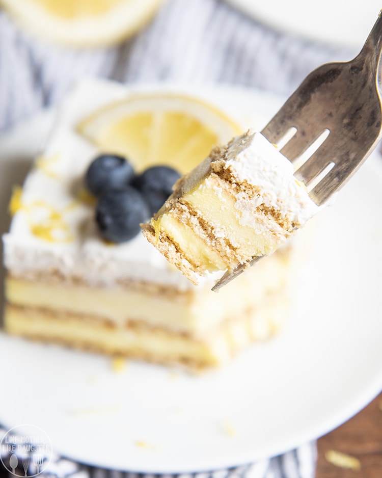 A forkful of lemon ice box cake above a plate. 