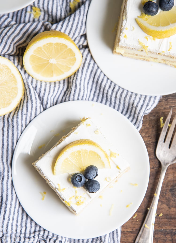 An overhead photo of a piece of ice box cake topped with a lemon slice and blueberries. 