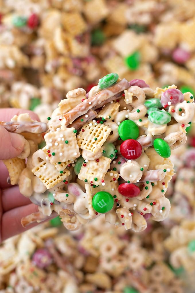 A hand holding cereal and candies dipped in white chocolate. 