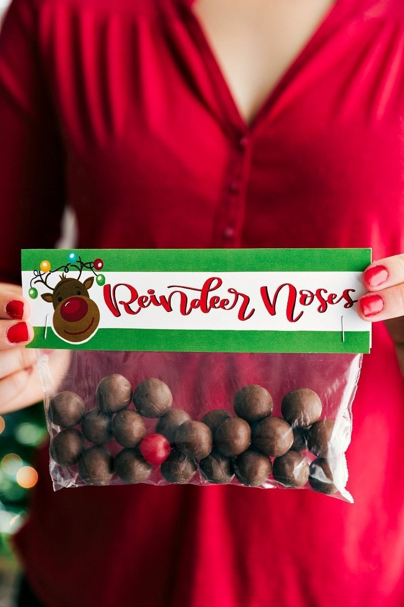 A person holding a bag of \"reindeer noses\" which are chocolate malt balls. 
