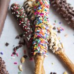 Chocolate and caramel covered pretzel rods topped with sprinkles.