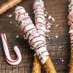 Two pretzel rods dipped in white chocolate and drizzled with chocolate, and topped with peppermint candy cane pieces.