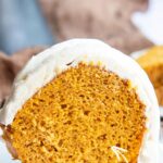 A piece of pumpkin bundt cake topped with cream cheese frosting.
