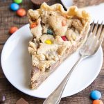 A piece of a cookie pie that is full of m&ms and other candy pieces.