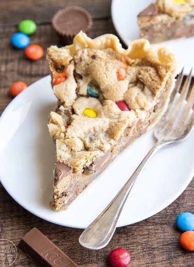 A piece of a cookie pie that is full of m&ms and other candy pieces.