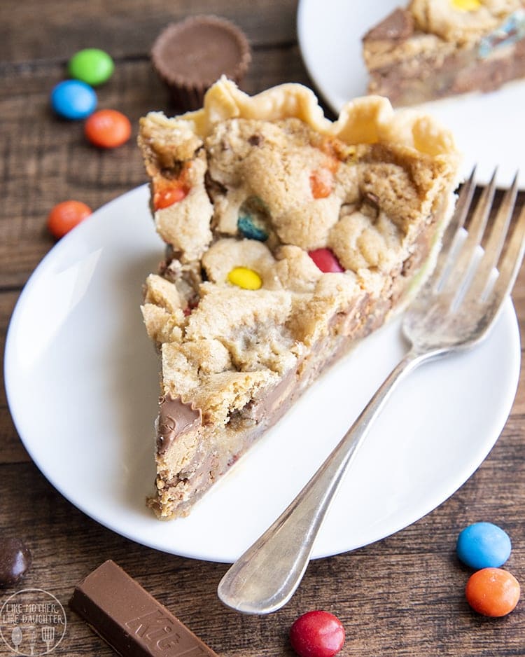 A piece of a cookie pie that is full of m&ms and other candy pieces.