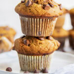 A stack of two bakery style pumpkin muffins on a plate.