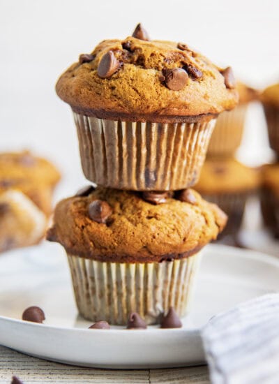 A stack of two bakery style pumpkin muffins on a plate.