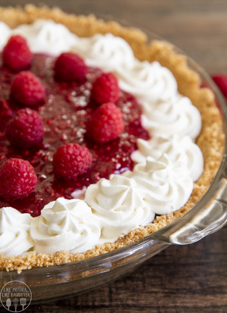 A raspberry cream pie with whipped cream flowers on the edges of the pie.
