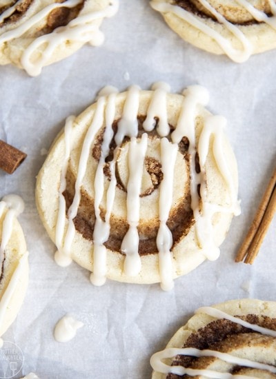 A sugar cookie with a swirl of cinnamon in the middle, and icing drizzled on top.