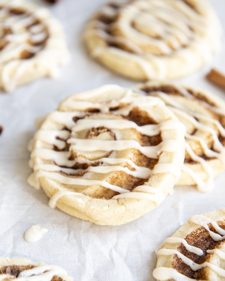 Two cinnamon roll sugar cookies topped with vanilla icing. 
