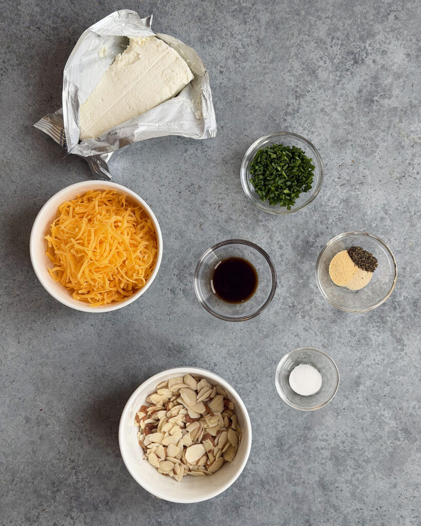 The ingredients needed to make a classic cheeseball in small bowls.