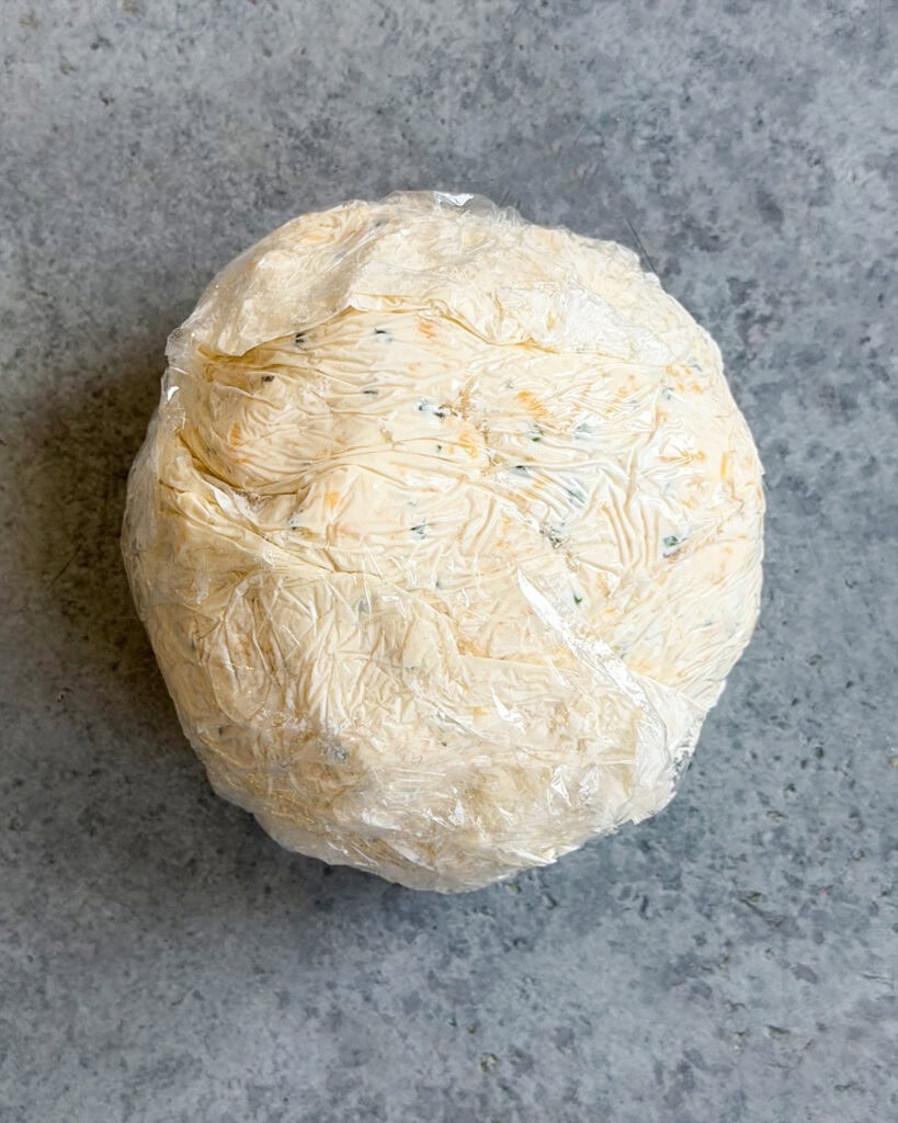 A cheese ball wrapped in plastic wrap.