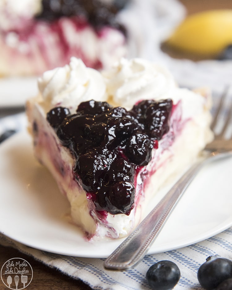 A piece of lemon sour cream pie topped with a homemade blueberry sauce.