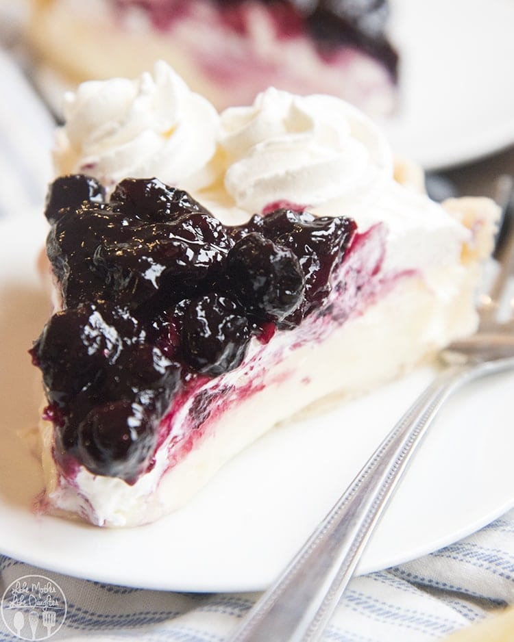 A slice of lemon cream pie topped with fresh blueberry sauce.