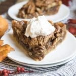 A piece of pecan pie with whipped cream on top.
