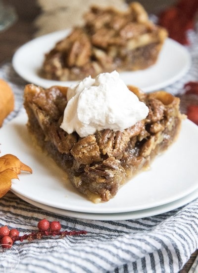 A piece of pecan pie with whipped cream on top.