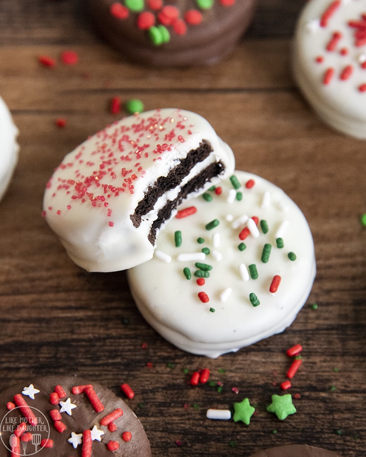 Two white chocolate covered oreos, in a pile. One has a bite out of it showing the Oreo in the middle.