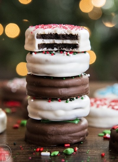 A stack of chocolate covered Oreos, the top is bitten in half showing the Oreo filling in the middle.