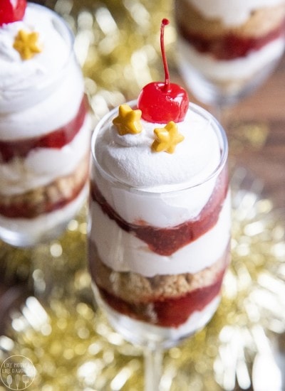 Above image of a glass with no bake cheesecake trifles with a cherry on top.