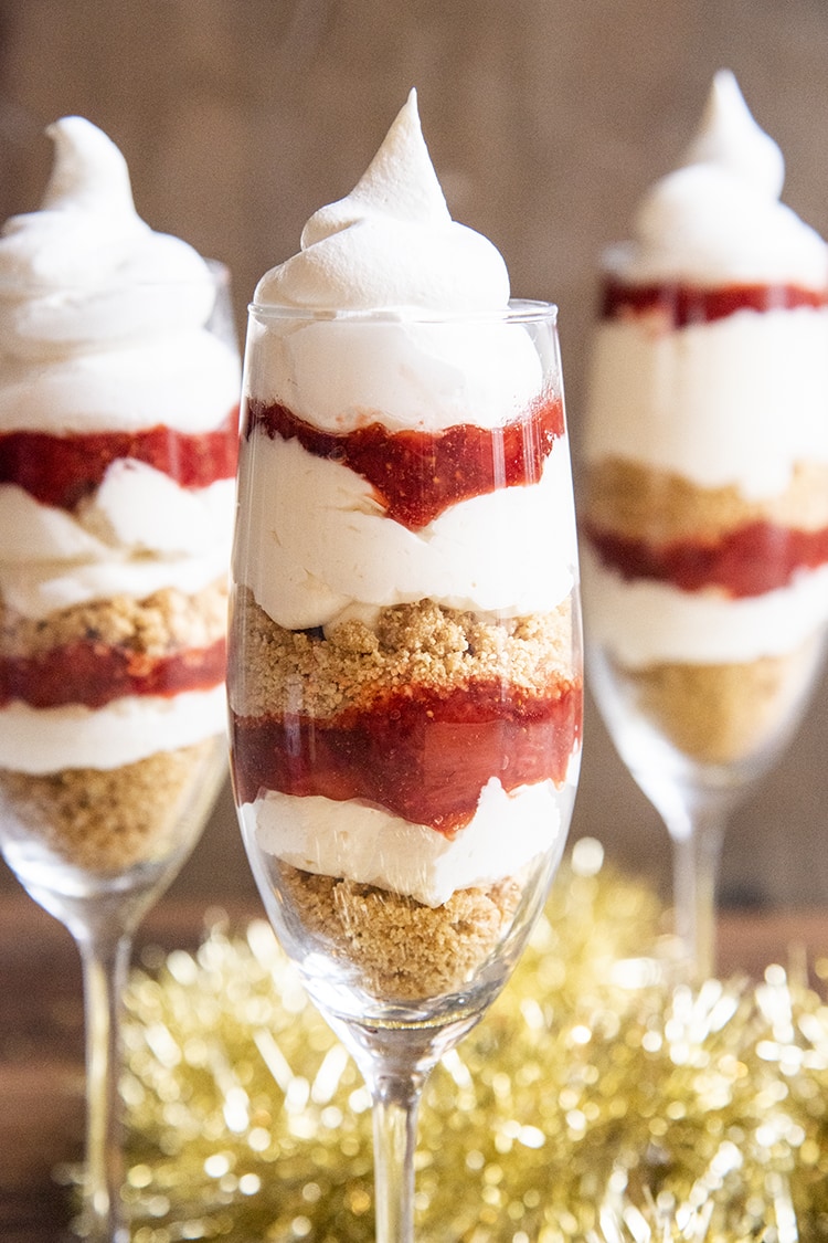 Close up image of a glass with no bake cheesecake trifles with a cherry on top.