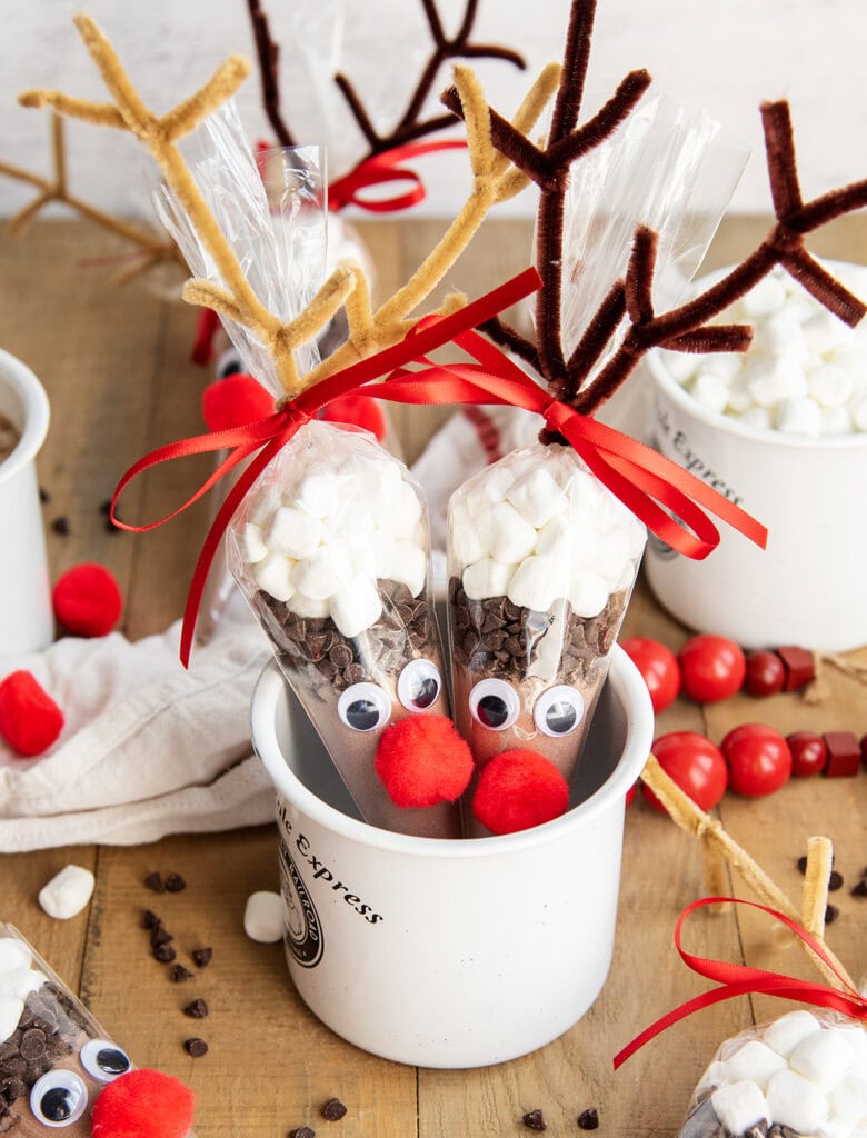 A mug full of two hot chocolate cones decorated to look like reindeer. 