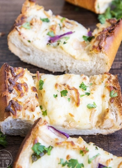 Slices of chicken alfredo french bread pizza on a wood backdrop with cheese and parsley on top.