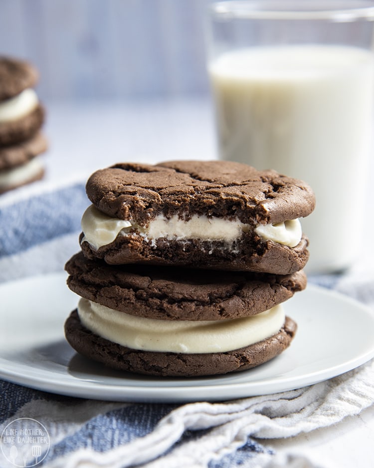 A close-up image of homemade oreos on a plate with a bite taken out of the top one.