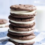 Close-up image of stacked homemade oreos on a blue and white cloth.