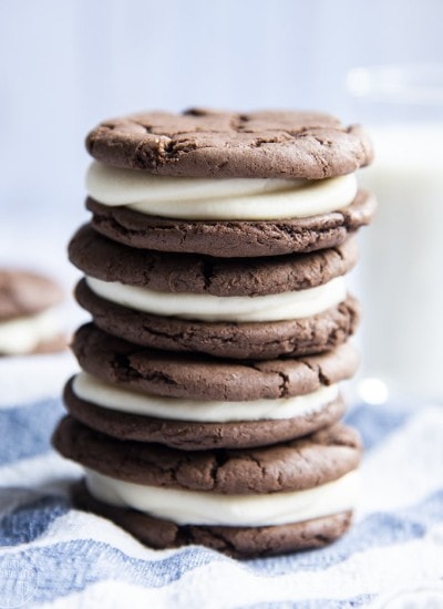 Close-up image of stacked homemade oreos on a blue and white cloth.