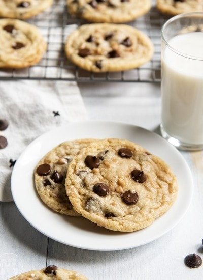 Above image of chocolate chip toffee cookies on a plate with milk behind and a cooling rack.
