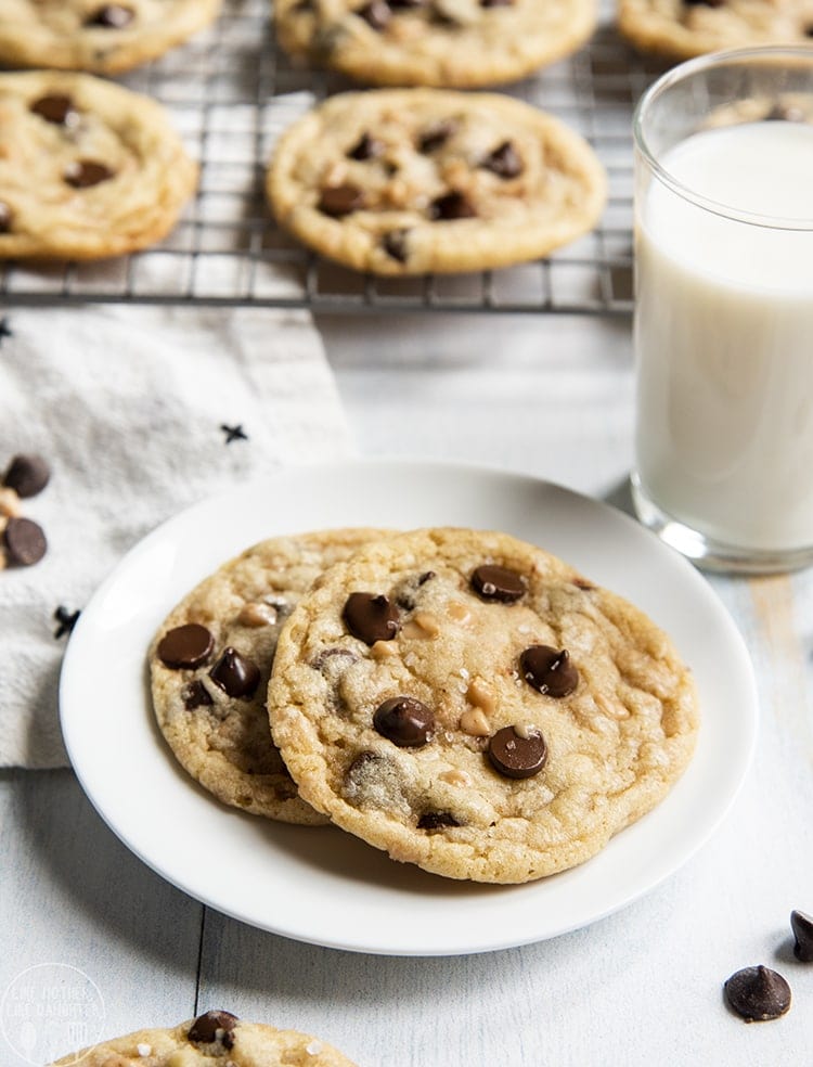 Above image of chocolate chip toffee cookies on a plate with milk behind and a cooling rack.
