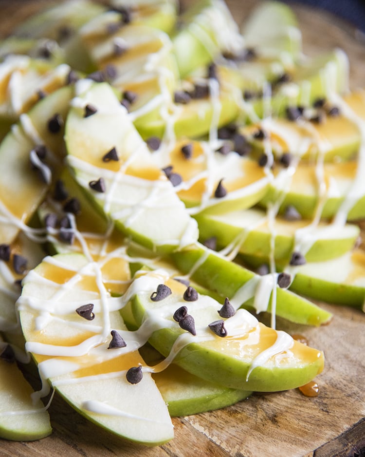 Close up image of apple nachos showing sliced apples with caramel and mini chocolate chips on top.