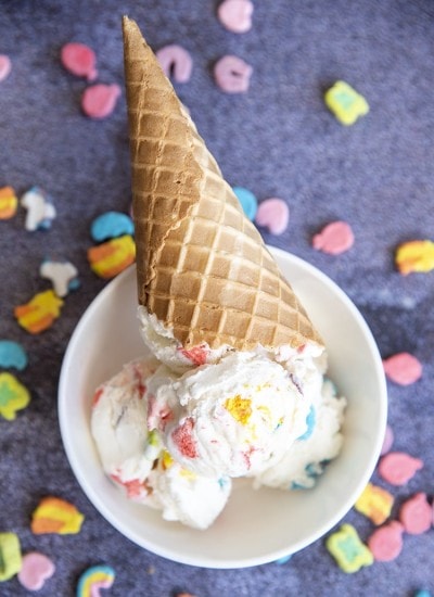 An ice cream cone full of white ice cream with colorful marshmallows.