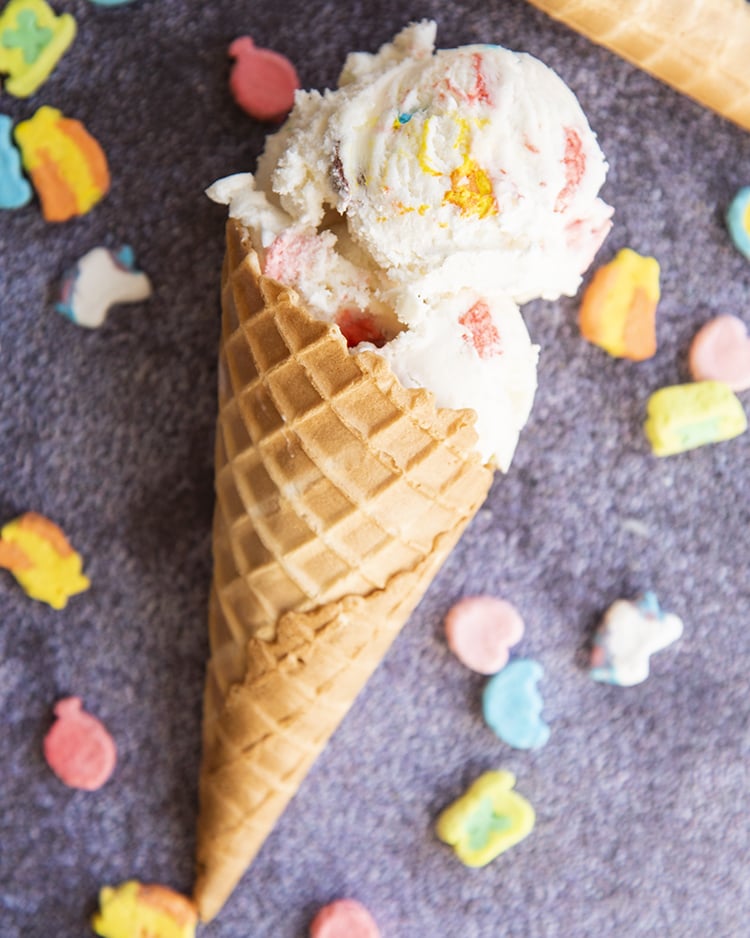 Above image of scoops of lucky charms cereal milk ice cream in a waffle cone.