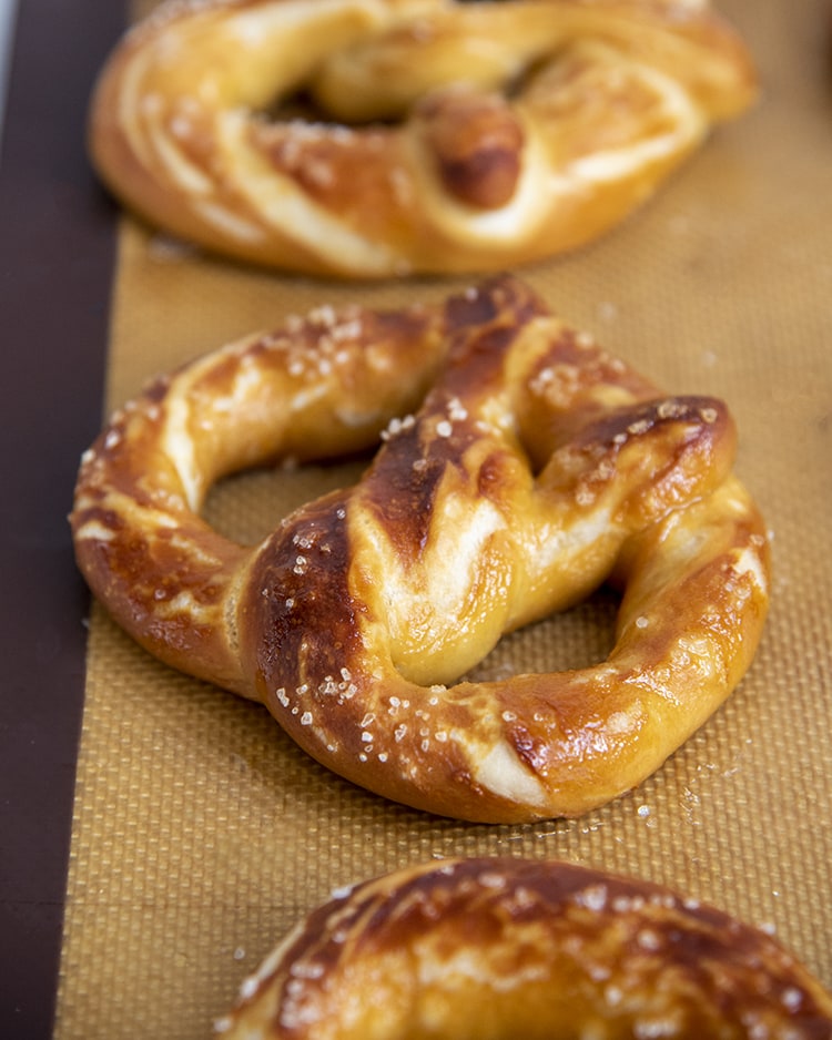 A close up of soft pretzels sprinkled with salt with golden brown crust.