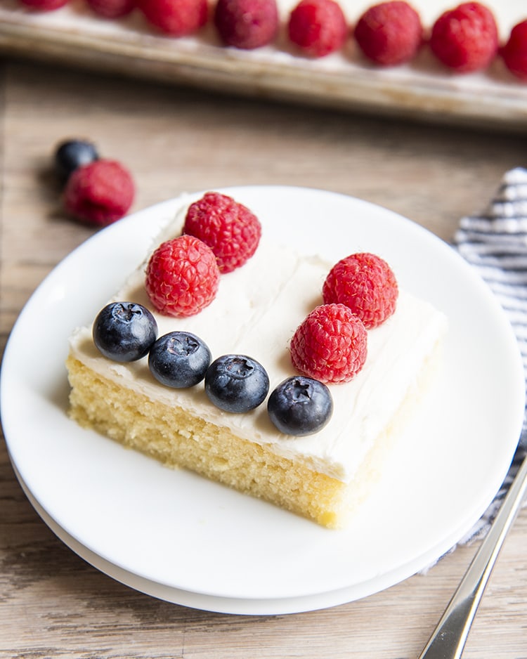 A slice of American flag cake with blueberries and raspberries in a flag design on top.