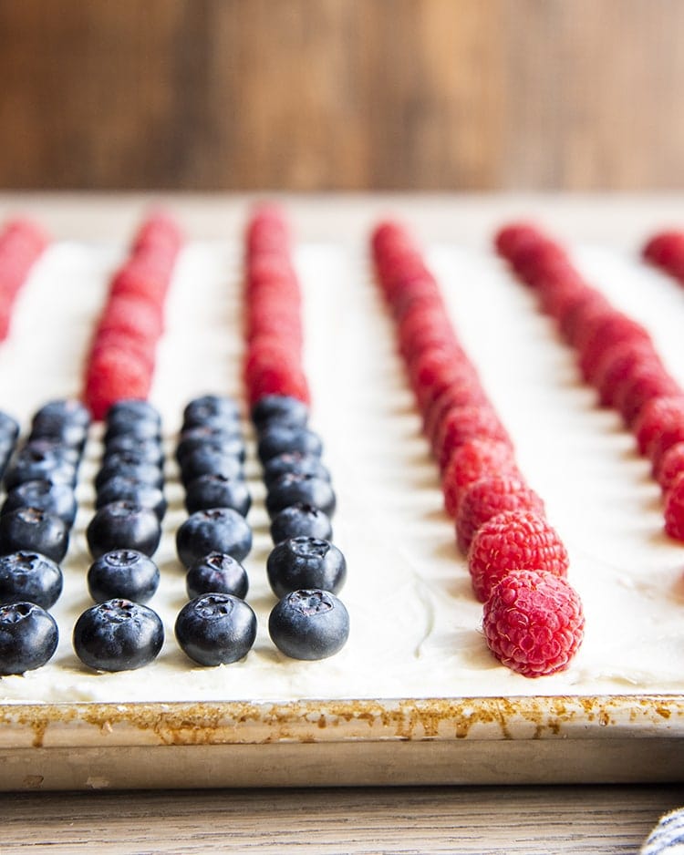 A white cake with blueberries and raspberries making a flag cake