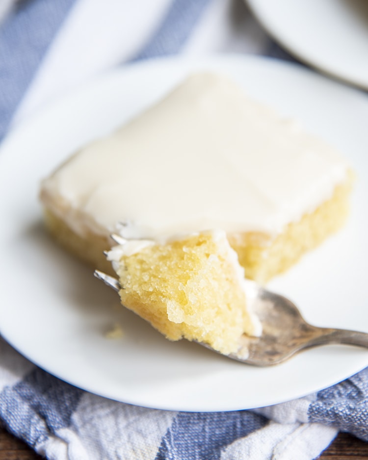 A slice of white texas sheet cake with a bite on a fork