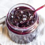 Blueberry Sauce in a jar with a spoon scooping some out