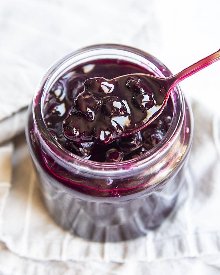 Blueberry Sauce in a jar with a spoon scooping some out