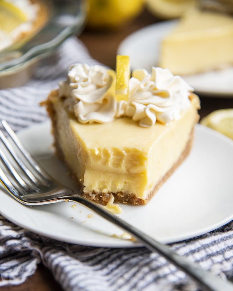 A slice of lemon cream pie with a bite taken out of it