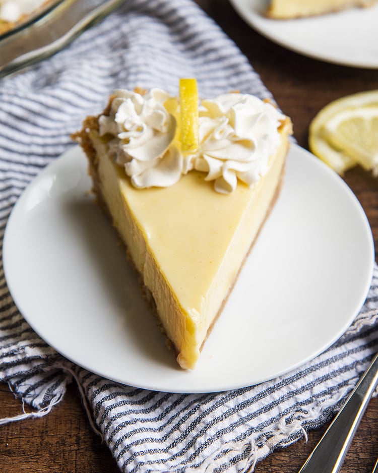 Lemon Cream Pie topped with whipped cream on a white plate