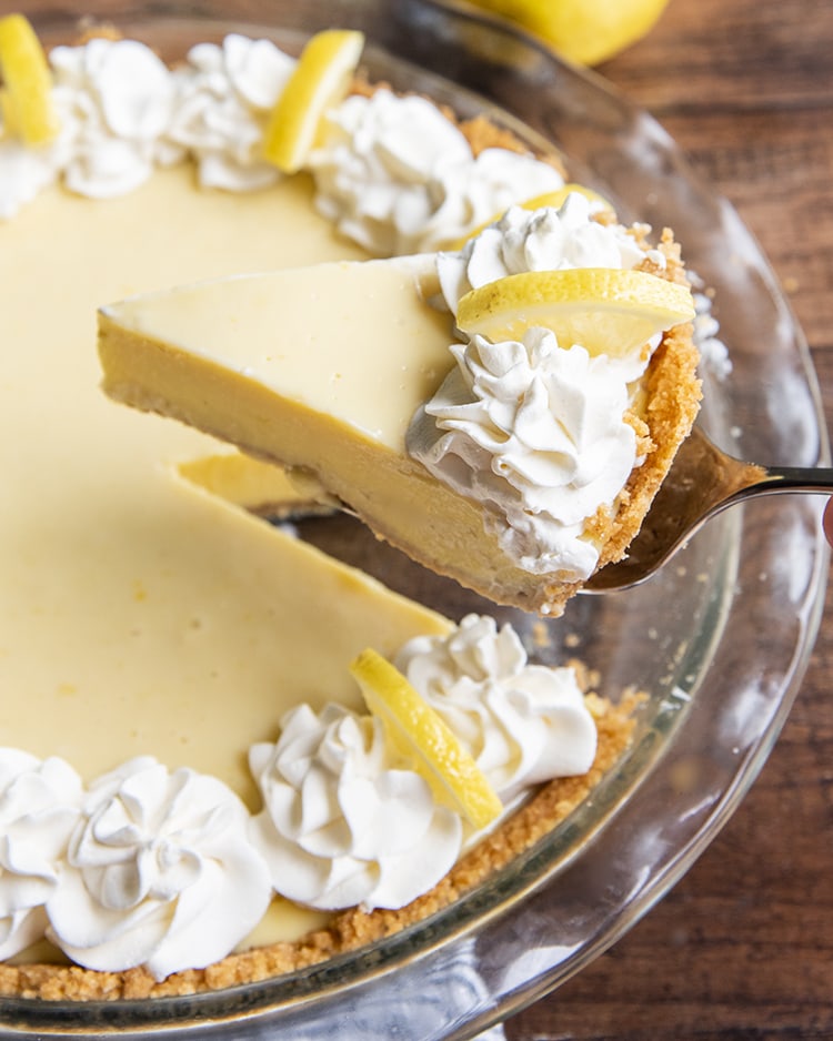 A slice of lemon cream pie being taken out of the pie dish