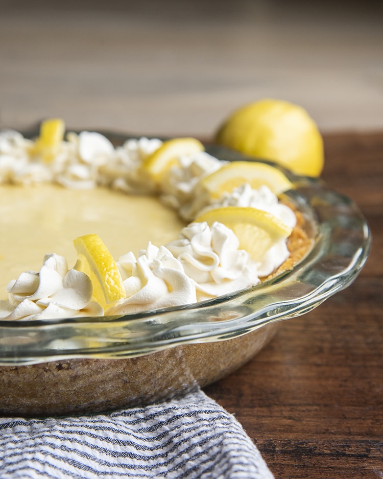 Lemon Cream Pie with Whipped Cream piped around the edges and a quarter of a lemon slice