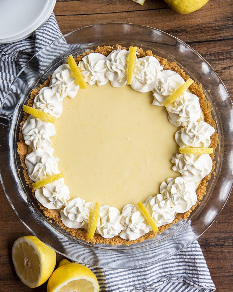 Lemon Cream Pie with Whipped Cream piped around the edges and a quarter of a lemon slice